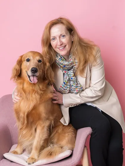 A beautiful portrait of a woman and her Golden Retriever, captured at a pet-friendly event. The simple pink backdrop really makes their smiles shine.