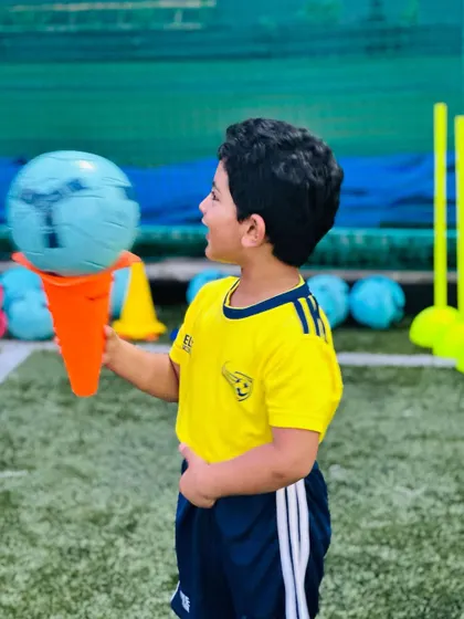 A young player playfully holds a football on a cone like an ice cream. We love the creativity and imagination of our kids.