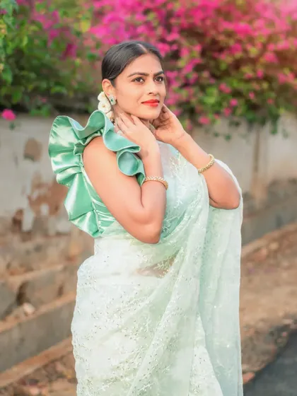 A model showing off the unique double-ruffle sleeve design of this custom green blouse.