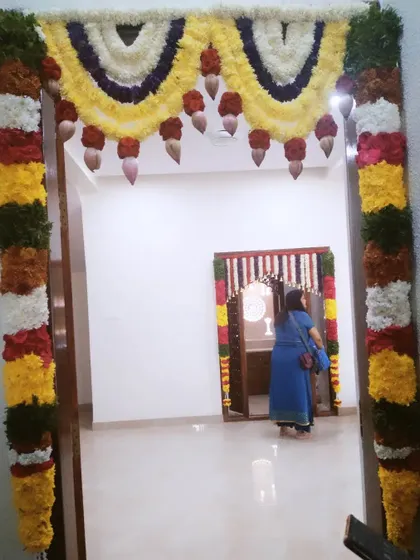 A full view of a decorated main door and a glimpse of the decorated pooja room inside, showing how I can create a cohesive look for your entire home.