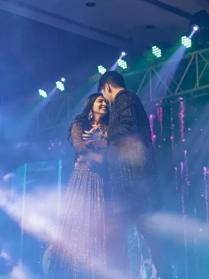 A tender moment between the couple on stage, with dramatic blue lighting creating a beautiful, moody atmosphere.