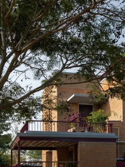 A close-up of the Eesha residence's balcony and facade, framed by the branches of a nearby tree.
