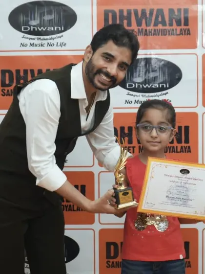 A teacher presents an award to his young, happy student.
