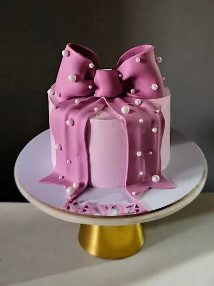 A mini version of the trending bow cake. This small cake is perfect for an intimate celebration and features a dramatic purple bow studded with edible pearls.