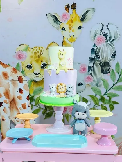 The centerpiece of the pastel safari party: a lovely cake adorned with cute fondant animals, placed on the pink jeep cart.