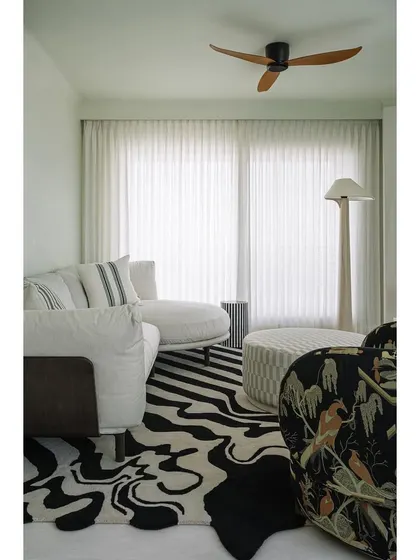 Another view of the family lounge, showcasing the eclectic mix of furniture, including a dramatic patterned armchair and a unique black and white rug. It's a space that is collected rather than chaotic.