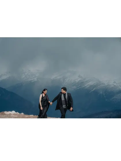 A couple holding hands and walking along a snowy ridge. This shot captures a sense of journey and togetherness against a powerful natural backdrop.