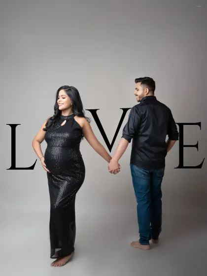 A modern and stylish maternity portrait with a graphic "LOVE" overlay. The couple holds hands, symbolizing their partnership as they step into this new chapter together.