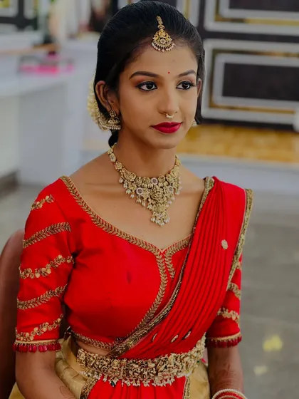 A simple yet elegant look for a pre-wedding function. The bright red blouse is paired with a classic gold necklace and subtle makeup.
