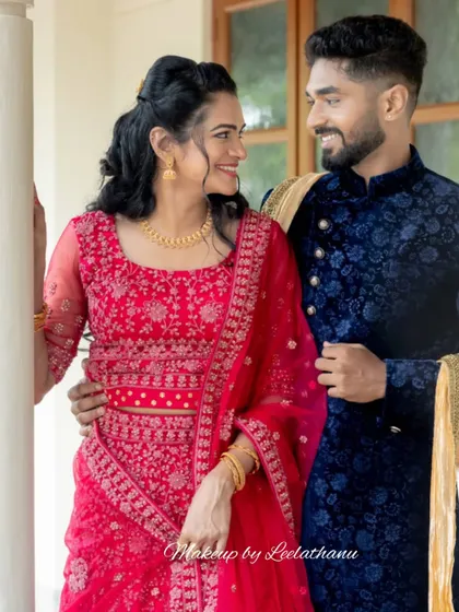 A picture-perfect couple at their engagement. The bride-to-be has a natural, glowing makeup look that enhances her features, paired with a beautiful red lehenga.