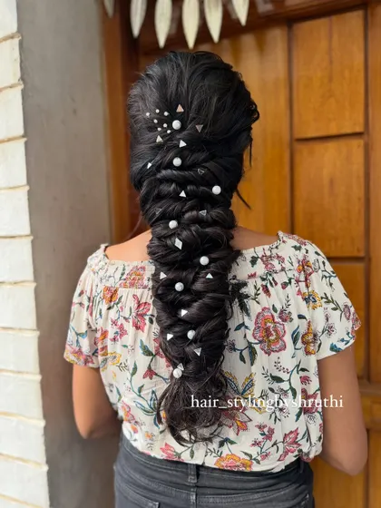 A detailed fishtail braid adorned with pearls and geometric clips. The combination of different accessories adds a unique and modern texture to the hairstyle.