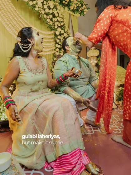 A playful moment during the Haldi ceremony, with the bride and groom covered in turmeric paste.