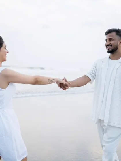 A playful "follow me to" style shot on the beach, capturing the fun and connection of the couple.