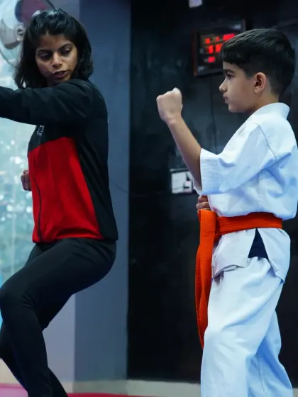 I work one on one with a young orange belt, refining his blocking technique. Individual coaching helps students master the details.