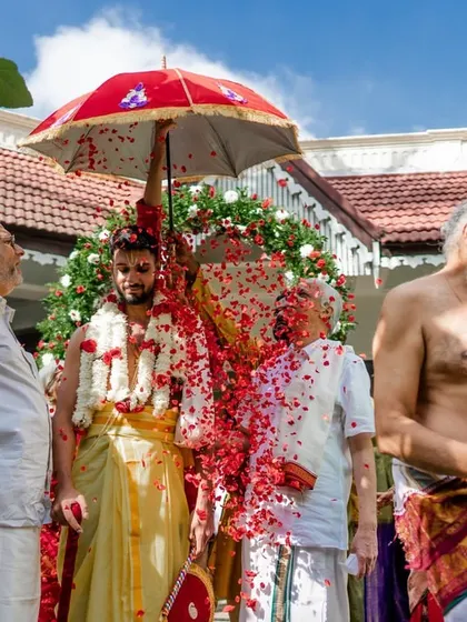 A groom is showered with flower petals during a traditional ceremony, a moment of vibrant celebration.