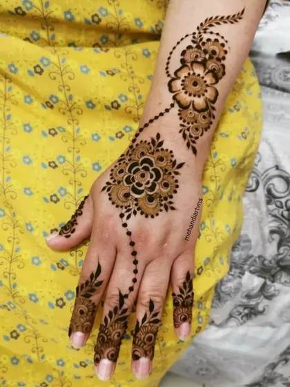 A single-hand view of a floral vine design. Notice how the pattern elegantly trails from the wrist to the finger, a key characteristic of Arabic and modern henna styles.