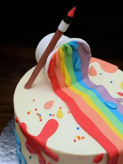 A close-up of the fondant details on the artist cake. The spilling paint bucket, paintbrush, and colorful drips are all handcrafted to create a playful and edible work of art.