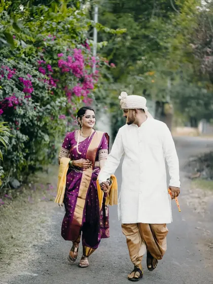 A happy walking shot of the couple in their traditional Maharashtrian outfits, sharing a smile as they walk together.