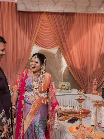 The happy parents-to-be, Kajal and her husband, admiring the traditional food table we set up for their baby shower.