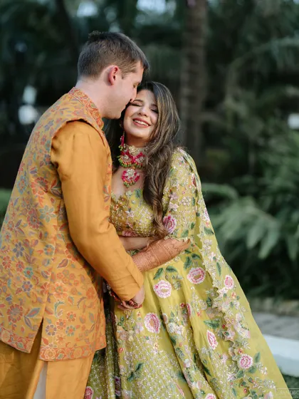 A sweet, candid moment of the groom kissing her forehead. The bride's smile is everything, and her makeup looks natural and radiant.