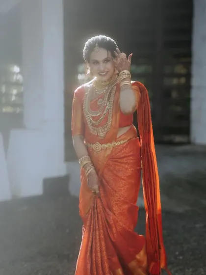 A bride in a stunning red saree, her joy and beauty captured in a moment of motion.