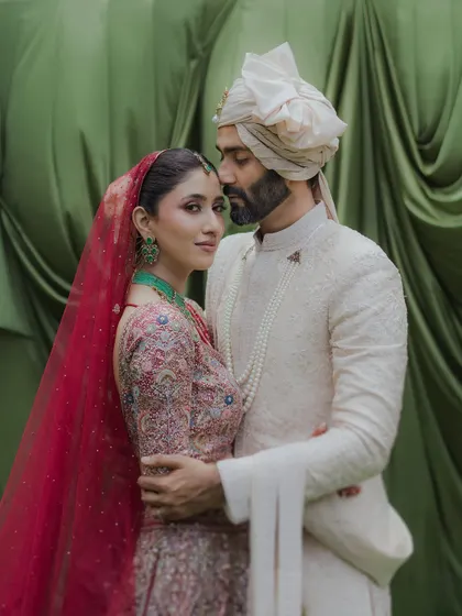 A classic portrait where the groom holds his bride close. Her gaze towards the camera and his towards her creates a beautiful dynamic, all set against a rich green backdrop at the Taj Lands End.