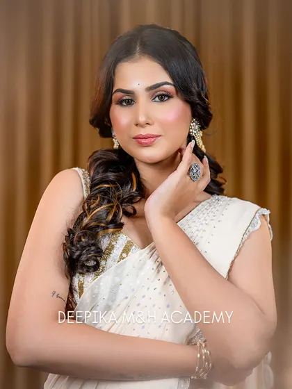 A portrait of the model looking at the camera. The hairstyle is a soft, romantic side-swept curl, which complements the elegant saree.