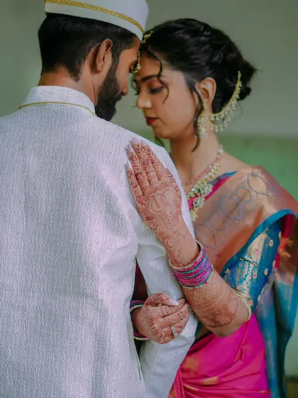 An intimate portrait focusing on the bride's mehndi adorned hand resting on the groom's shoulder. A simple, yet powerful, symbol of their bond.