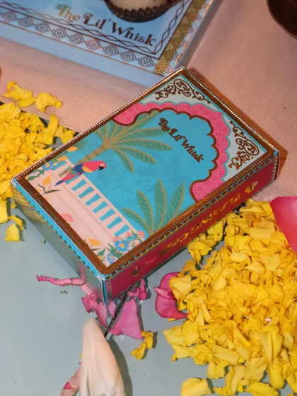 A single box of our custom playing cards, surrounded by flower petals. The vibrant, festive packaging makes them a beautiful and unique gift.