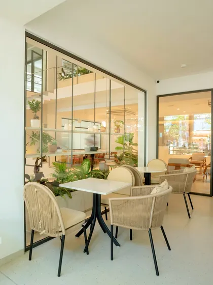 Our outdoor seating area, where you can enjoy your coffee surrounded by greenery. The glass walls blur the line between indoors and outdoors.
