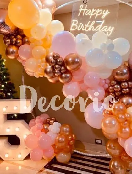 A beautiful 25th birthday party featuring a circular backdrop with a neon sign. The decor is brought to life with large marquee numbers and a pastel and rose gold balloon arrangement.