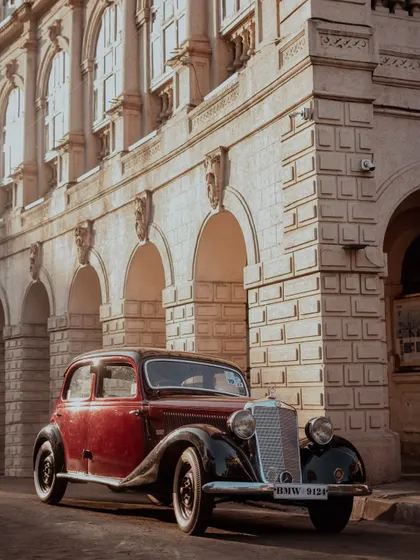A stunning vintage Mercedes parked in front of a historic building in Mumbai, bathed in golden hour light. This shot is a perfect slice of history in the present moment.