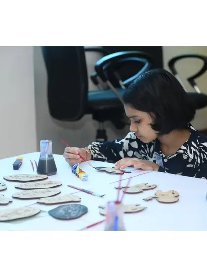 A young artist carefully paints a wooden cutout. For this corporate event, we created custom magnets shaped like the company's iconic product, the Mahindra Thar.