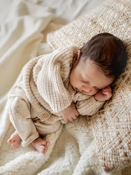 A newborn sleeping peacefully on a comfy bed. Lifestyle sessions are perfect for capturing these serene moments in a natural, unposed way.