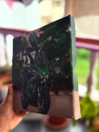 Holding the finished biker painting, showing the side view of the canvas.