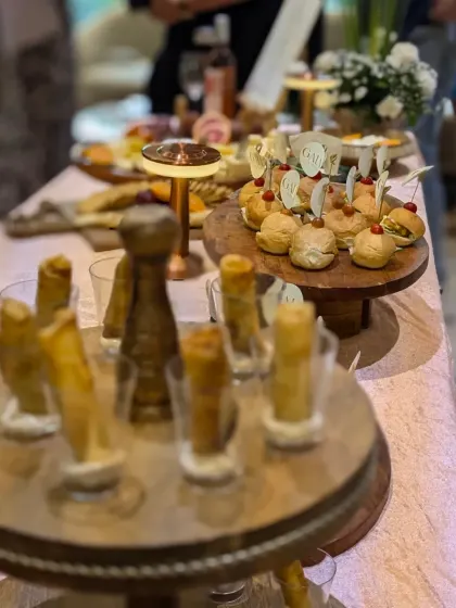 A sophisticated setup for a luxury brand event, showcasing tiered displays of mini burgers and elegant truffle cigar rolls. I ensure the presentation always matches the caliber of the occasion.