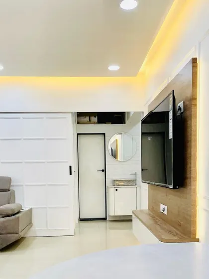 A view of a completed living room showcasing how different elements come together. The design connects the seating area, a compact washbasin nook, and the entryway with consistent wall paneling and warm, layered lighting.