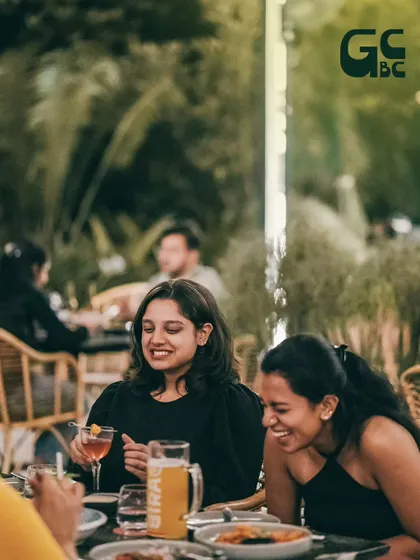 Bright smiles and infectious vibes. Two friends sharing a laugh over drinks and food.