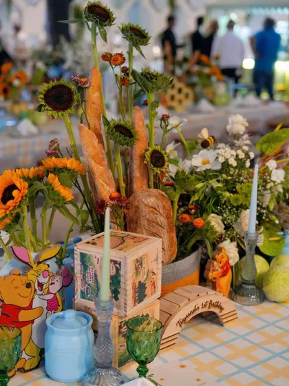 A unique centerpiece combining fresh baguettes, sunflowers, and Winnie the Pooh characters, perfectly capturing the rustic charm of the theme.