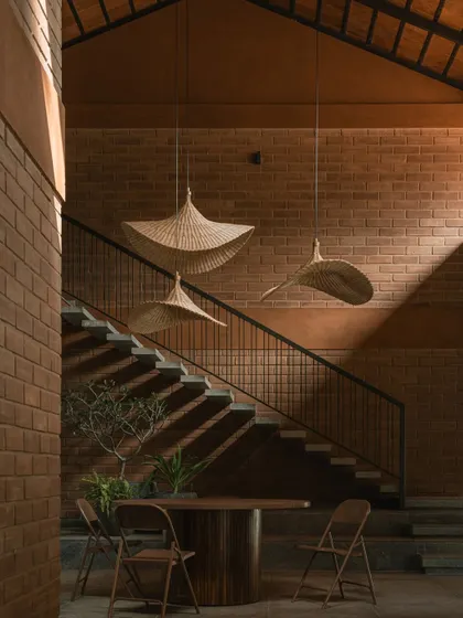 The sculptural bamboo pendant lights create a focal point in this seating area. Their organic shape contrasts beautifully with the linear geometry of the staircase and the texture of the brick wall.