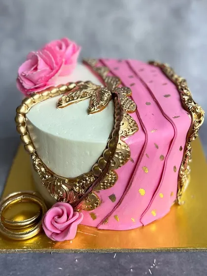 An intricate Karwa Chauth cake designed to look like a pink saree with golden jewelry. It's a beautiful and symbolic way to celebrate the bond of marriage.