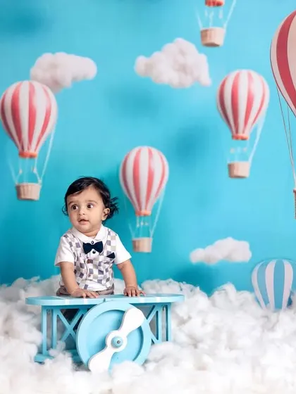 A seven-month-old explorer on a hot air balloon adventure. This imaginative setup with clouds and a bright blue sky is perfect for capturing a baby's sense of wonder.