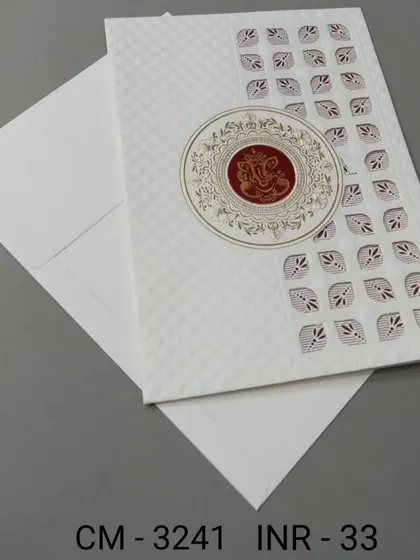 A modern white invitation with a geometric pattern and a central Ganesha emblem. This card is a great choice for those who want a blend of contemporary style and tradition.