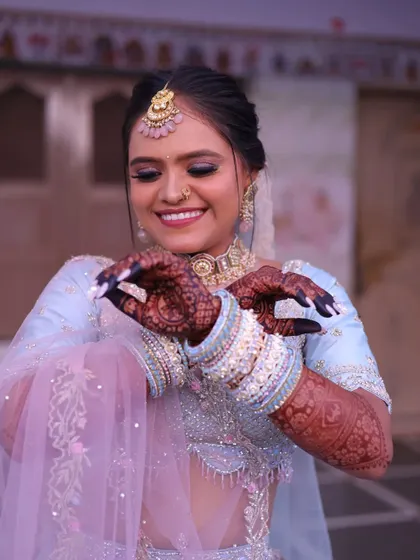 A lovely Gujarati bride admiring her intricate henna. The makeup is kept fresh and radiant with a pop of color on the lips.