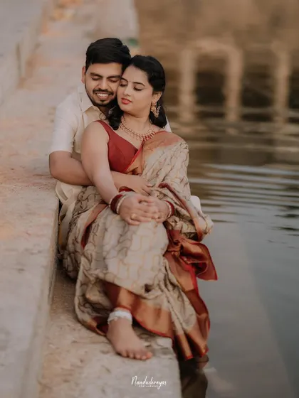 A tender moment by the water's edge, with the couple embracing as the bride dips her feet in the pond.