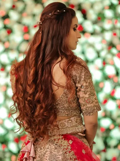A beautiful half-up hairstyle with a small braid detail and long, flowing curls. This is a romantic and feminine look, perfect for a reception.