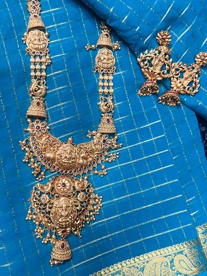 A close-up of a stunning temple jewellery long necklace and matching earrings. The intricate details and goddess motifs are what make these pieces so special.