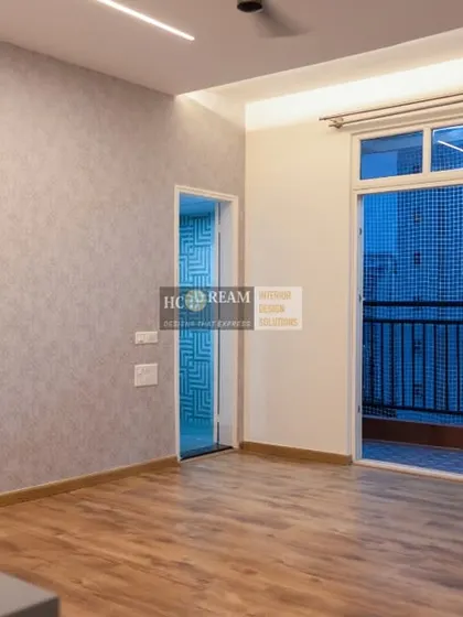 A view of the living space in Deepak and Anju's 3BHK apartment at Prestige Shantiniketan. The wooden flooring and light grey wallpaper create a modern and calming atmosphere.