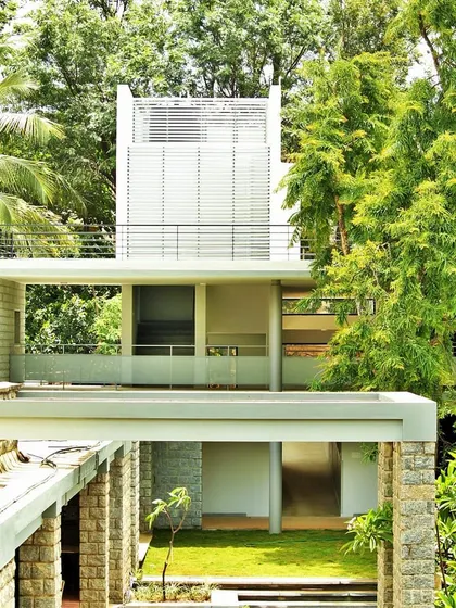 The new ward block at Karunashraya, seen through the trees. The design uses verandas and a cantilevered roof to blend with the existing buildings and landscape.