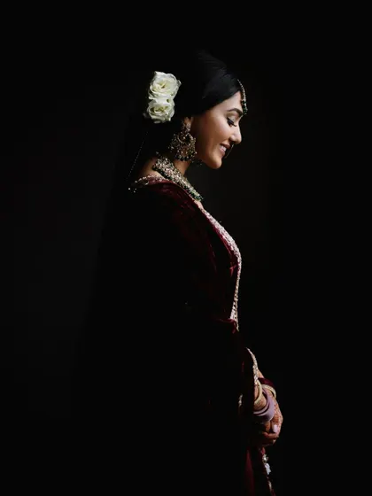 A stunning, low-light bridal portrait from a wedding in the USA. The use of shadow and light creates a dramatic and artistic image that highlights the bride's features.